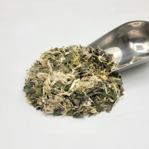 Mélange de tisane bio Stomacool de l'herboristerie du Docteur Sammut avec une pelle à thé révélant des plantes médicinales pour l'acidité gastrique.
