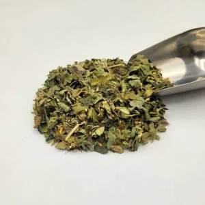 Mélange de plantes médicinales pour l'endométriose du Docteur Sammut, avec une pelle à thé, dans une herboristerie.